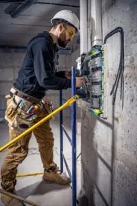 alt: Irvine, CA electrician installing electrical panel switch with drill